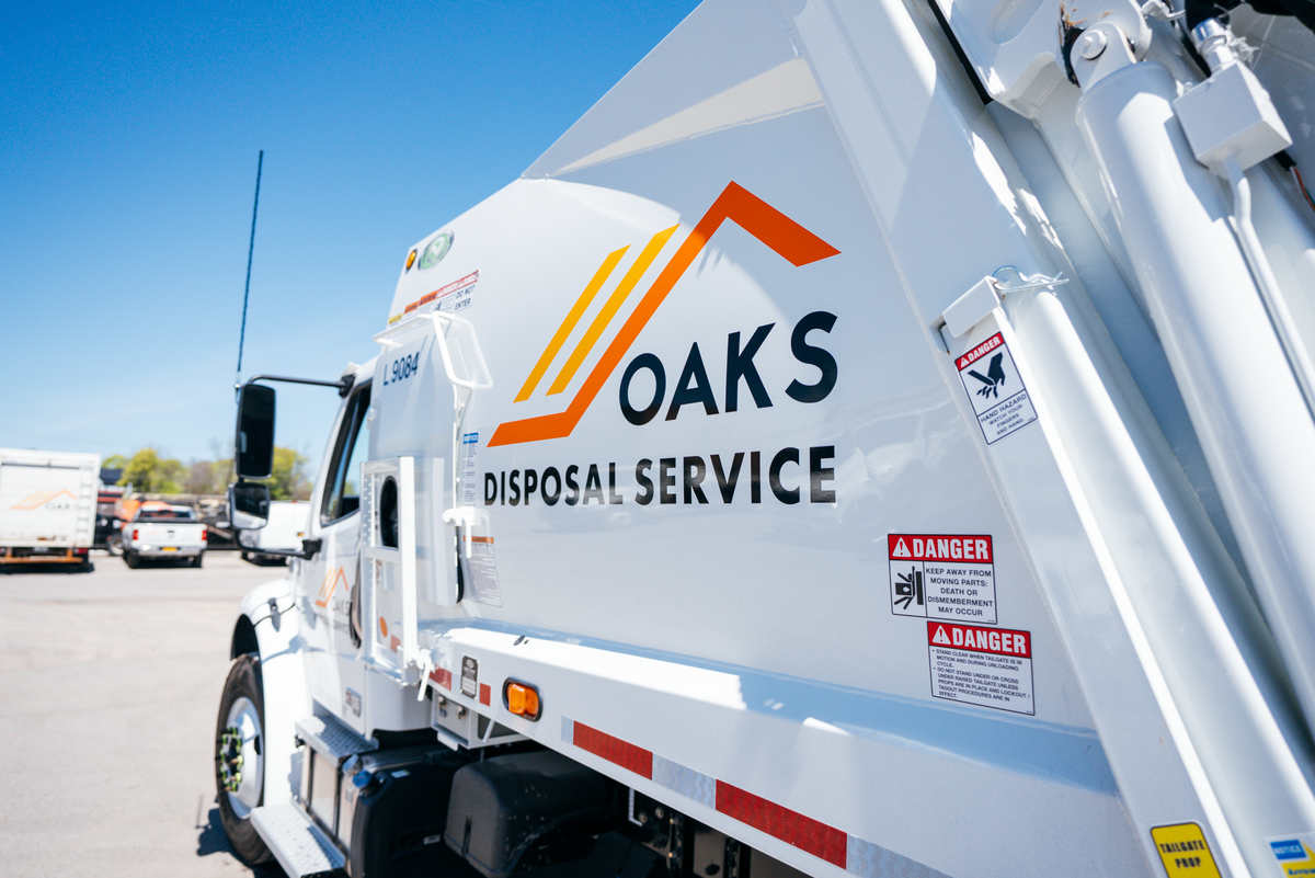 A white Oaks Disposal Service truck parked outside.