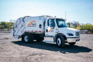 A white garbage truck with OAKS Waste Services logo