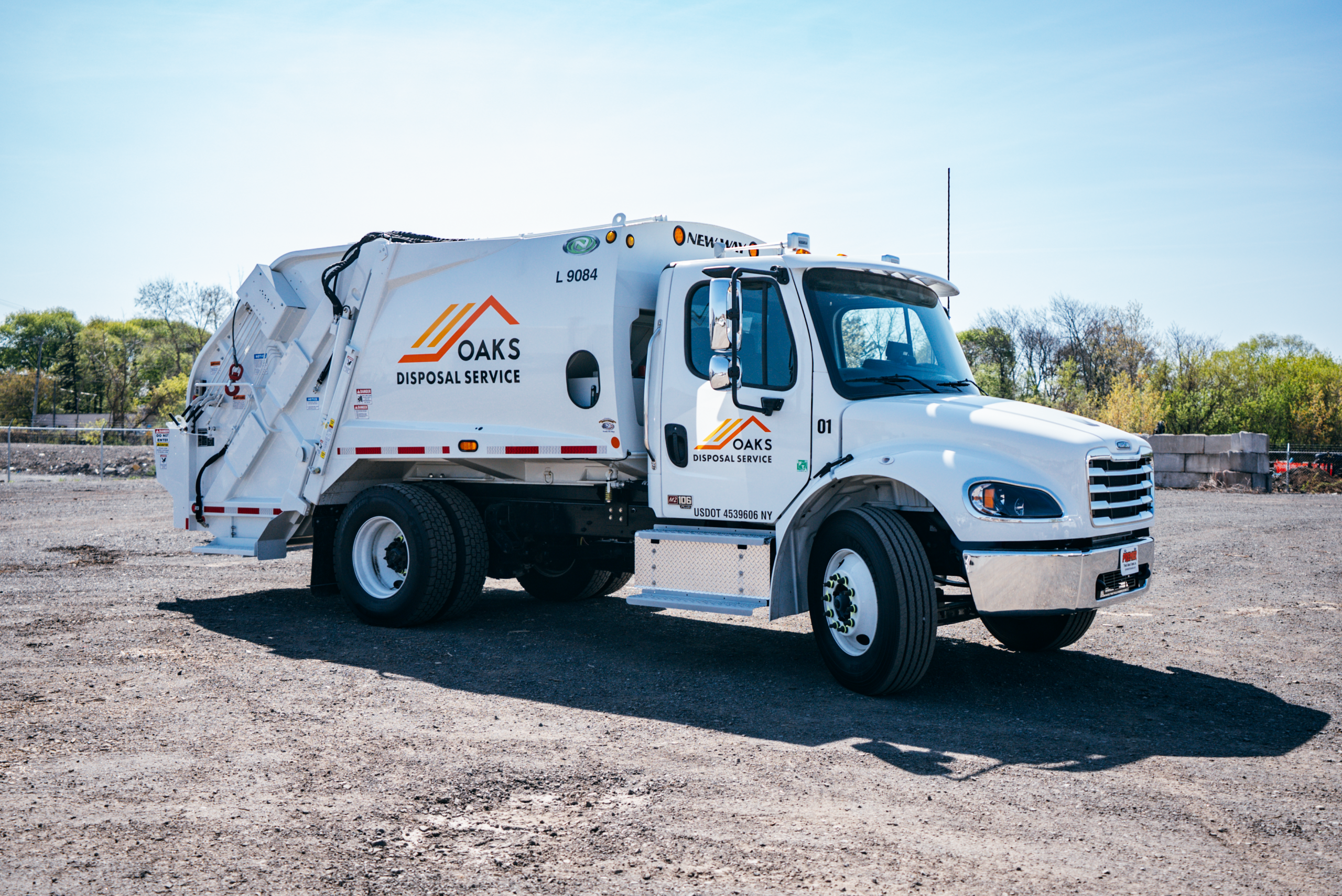 A white garbage truck with OAKS Waste Services logo