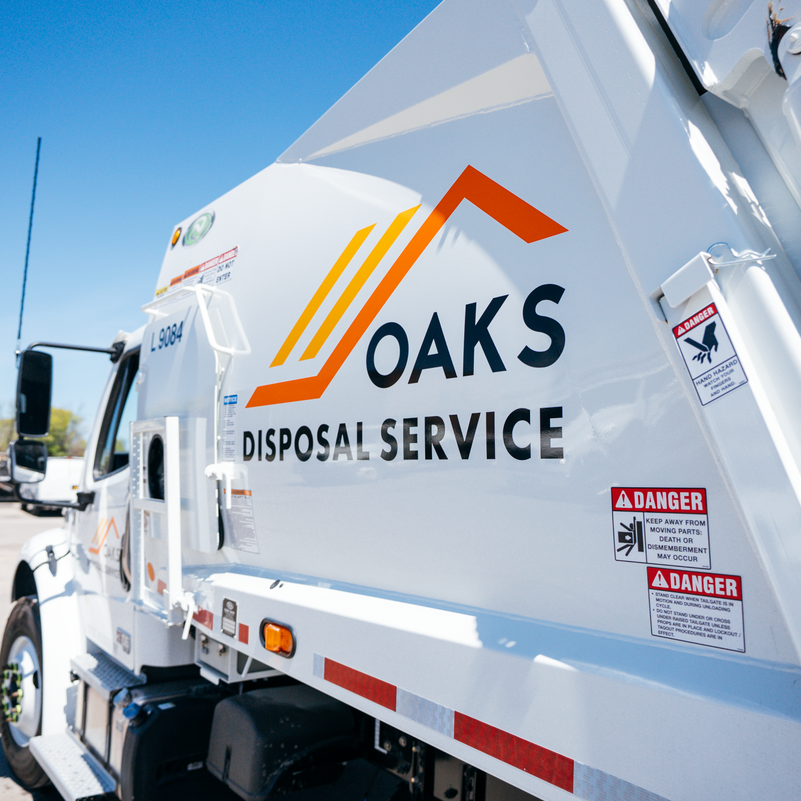 A white Oaks Disposal Service truck parked outside.