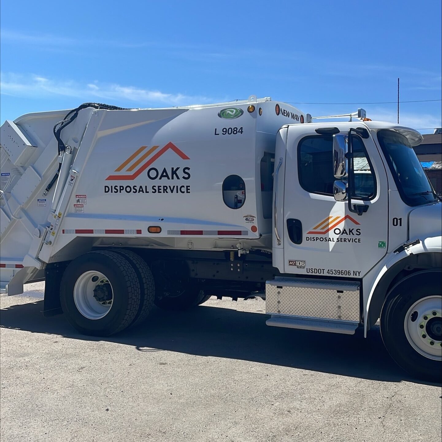 A white waste management truck with Oaks Landscaping Services logo